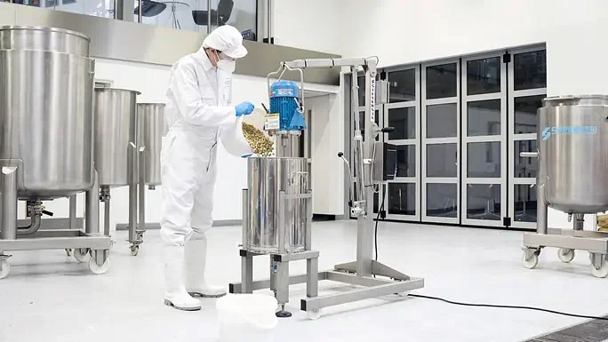 Operator adding ingredients to a vessel with a Silverson batch mixer on a mobile floor stand