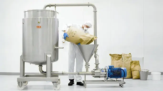 Operator loading powder into a Silverson Flashmix powder/liquid mixer
